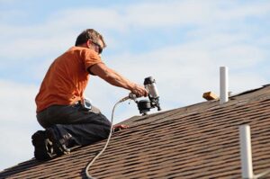 Homeowner inspecting roof shingles and gutters from the ground beside a house in autumn